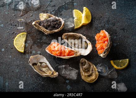 Entrantes y aperitivos de mariscos: Ostras frescas abiertas, caviar negro y tartar de salmón Foto de stock