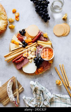 Tabla de quesos con galletas, grissini, salami y uvas Foto de stock