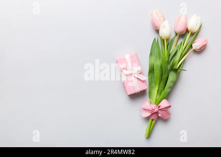 Flores de tulipanes rosadas y regalo o caja de regalo sobre fondo de mesa de color. Día de las madres, cumpleaños, día de las mujeres, concepto de celebración. Espacio para el texto top vi Foto de stock