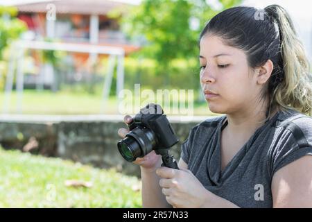 primer plano de una chica blogger sosteniendo una cámara en la mano con la que graba sus vlogs de viaje Foto de stock