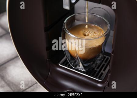 Moderna cafetera de cápsulas con goteo de espresso, taza, vainas y granos  en mesa grunge gris Fotografía de stock - Alamy