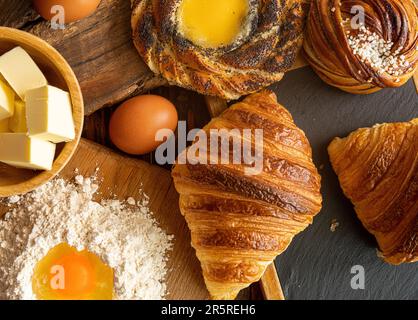 Bollo de canela sueco recién horneado, cruasanes y crema spandauer, mantequilla, huevos y harina Foto de stock