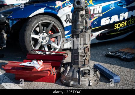 Detalle de una caja de cambios manual y una caja de herramientas en el suelo, reparando el coche de carreras en la calle Foto de stock