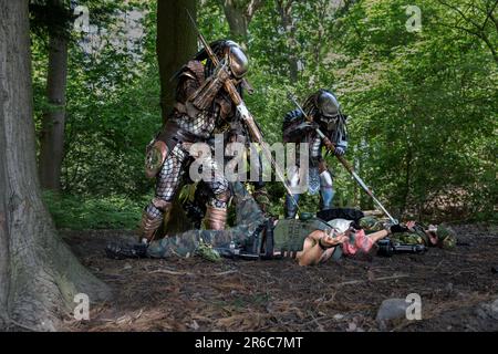 HARROGATE, REINO UNIDO - 3 DE JUNIO DE 2023. Un retrato de un cosplayer vestido como un Predator alienígena en traje realista al aire libre en un entorno de bosque Foto de stock