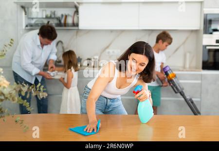 Familia feliz con dos niños haciendo limpieza en la cocina Foto de stock