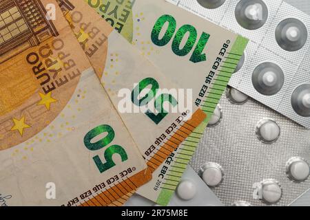 Primeros planos de billetes europeos de 50 y 100 euros y píldoras médicas. Foto de stock