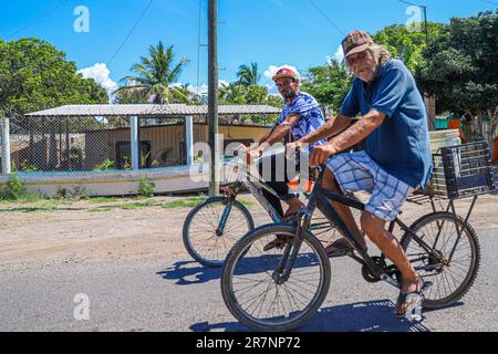 Dos hombres en bicicleta en la comunidad pesquera o puerto de