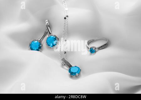 Hermosa joyería con piedras preciosas azul claro en tela blanca Foto de stock