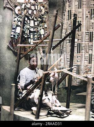 Un Ashanti tejiendo tela de seda en el Gold Coast Pavilion en la Exposición del Imperio Británico en Wembley, Londres Fecha: 1924 Foto de stock