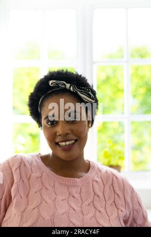 Retrato de mujer afroamericana feliz de talla grande por ventana Foto de stock