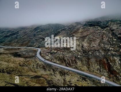 Carretera de asfalto en terreno montañoso en niebla Foto de stock