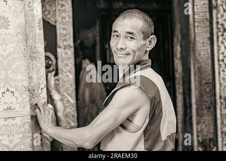 Tibetano sonriente frente a la entrada de un templo en el monasterio Kumbum, Xining, China Foto de stock