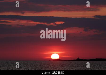 Puesta de sol sobre el mar de Irlanda en Dinas Dinlle en la costa del norte de Gales Foto de stock