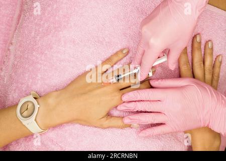 Inyección de mesoterapia de rejuvenecimiento de la piel de la mano para el paciente femenino. Tratamiento antienvejecimiento en clínica de cosmetología. Mano de esteticista en guantes con jeringa. Foto de stock