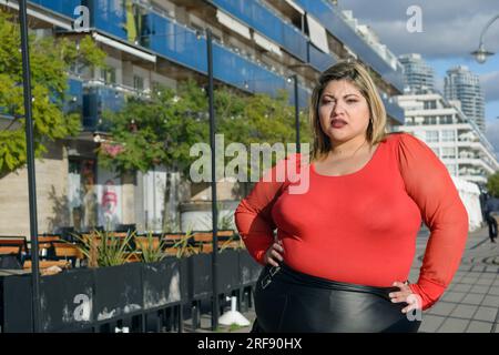 Joven hermosa mujer latina de talla grande posando en el parque con falda  tutú negra y suéter rojo