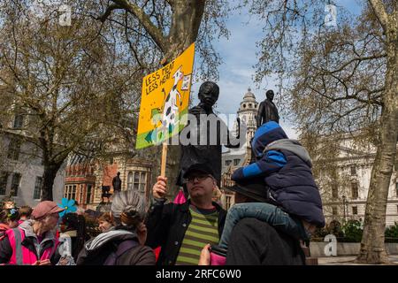 Londres, Reino Unido, 2023. El Día de la Tierra, un activista por el clima sostiene un cartel que dice, menos carne menos calor, frente a la estatua de Nelson Mandela Foto de stock