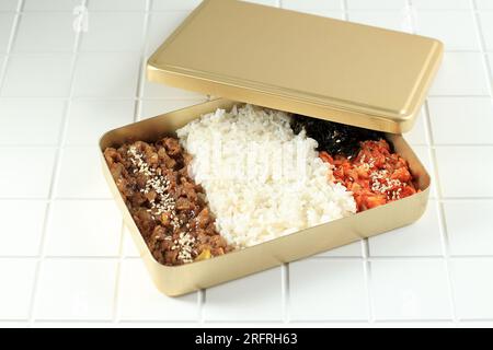 mano femenina preparando dosirak o caja bento coreana, servida en una  lonchera de metal dorado para mantener la comida caliente. 11273335 Foto de  stock en Vecteezy