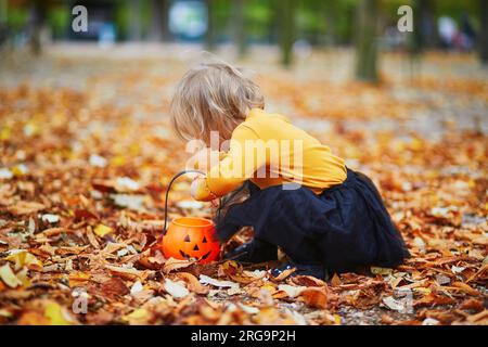 Niña adorable en camiseta naranja y tutú negro jugando con