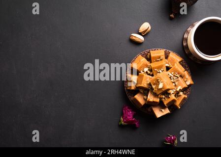 Sorbete de caramelo con nueces pistachos y café turco sobre fondo negro, espacio de copia. Postre tradicional de Oriente Medio iris o sorbete. Foto de stock