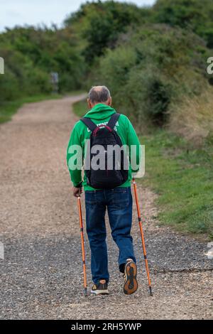 hombre mayor de mediana edad salir a dar un paseo por el campo con bastones para caminar para ayudar. bastones noruegos para caminar. Foto de stock