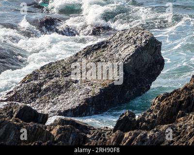 Una gran roca con agua del océano arremolinándose alrededor de ella Foto de stock
