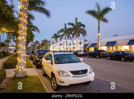 Nápoles, Florida, EE.UU.. Vista a lo largo de la 13th Avenue South, bordeada de palmeras, en el corazón del principal distrito de restaurantes de la ciudad, al atardecer. Foto de stock