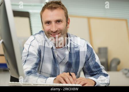 feliz hombre de negocios casual sentado frente a la computadora portátil Foto de stock