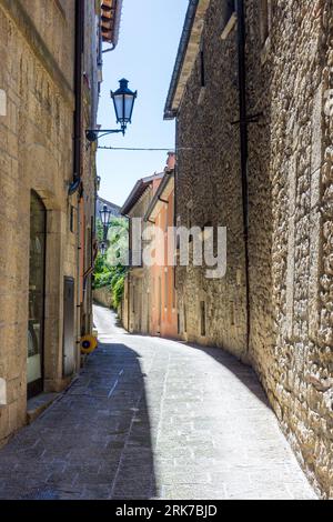 Una calle adoquinada tradicional con edificios antiguos que bordean la carretera en la República de San Marino Foto de stock