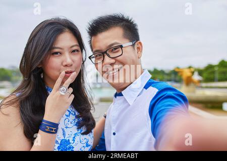 Hermosa pareja asiática de turistas que pasan sus vacaciones en París y se toman selfie con un teléfono móvil, la chica muestra un signo de V, un gesto popular Foto de stock