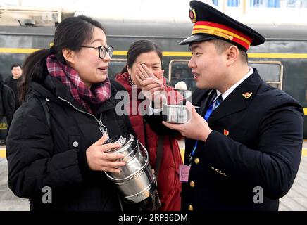 (190219) -- ZHENGZHOU, 19 de febrero de 2019 (Xinhua) -- Zhu Kangyu come tangyuan preparado por Liu Xiaojing en la plataforma de la estación de tren de Zhengzhou en Zhengzhou, provincia central de Henan, China, 19 de febrero de 2019. Cuando el tren K4364 llega a la estación de tren de Zhengzhou, Liu Xiaojing, que está embarazada de más de seis meses, se dirige a reunirse con su marido en la plataforma el día del Festival de la Linterna China, un día que simboliza la reunión familiar. Después de más de dos semanas de separación, la pareja tiene solo 20 minutos para reunirse antes de que comience el tren. El marido Zhu Kangyu, que trabaja como tren Foto de stock
