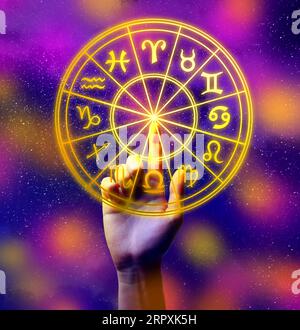 Astrology. Woman touching zodiac wheel on bright background, closeup Stock Photo