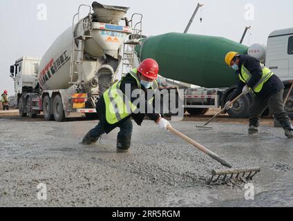 210114 -- SHIJIAZHUANG, Jan. 14, 2021 -- Workers harden the road surface on the construction site of a centralized medical observation center in Shijiazhuang, capital of north China s Hebei Province, Jan. 14, 2021. Construction workers on Wednesday started building a centralized medical observation center in Shijiazhuang, capital of north China s Hebei Province, where clustered COVID-19 cases occurred. The isolation center will likely cover 33 hectares of area near a village in Zhengding County, Shijiazhuang. Three integrated housing producers in Tangshan City, Hebei, have been entrusted to pr Stock Photo