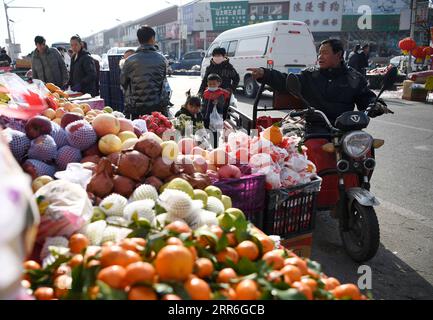 210214 -- YINCHUAN, 14 de febrero de 2021 -- Zhang Junming compra frutas en un mercado cerca de su nueva residencia en el sitio de reubicación de Binhe Jiayuan un día antes del Año Nuevo Lunar Chino en Yinchuan, en el noroeste de China, Ningxia Hui Región Autónoma, 11 de febrero de 2021. Zhang Junming, de 55 años, vivió una vez en el municipio de Hongbaiyang, un remanso económico en el sur de Ningxia. Cuando era joven, Zhang había resultado gravemente herido en un accidente, y por lo tanto sufrió de discapacidades en las piernas que le impidieron buscar oportunidades de trabajo en las grandes ciudades. Así que él y su familia tuvieron que ganarse la vida de los pobres rendimientos en la b Foto de stock