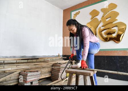 210426 -- JINAN, 26 de abril de 2021 -- Yang Hongwei procesa el bambú para hacer el esqueleto de una cometa en la aldea de Yangjiabu, ciudad de Weifang, provincia de Shandong del este de China, 16 de abril de 2021. Yang Hongwei, nacida en una familia de fabricación de cometas en Yangjiabu, se embarcó en su viaje de fabricación de cometas en 1982 bajo la guía de su abuelo. En los siguientes casi 40 años, Yang ha estado desarrollando la herencia cultural y ganó sus obras muchos reconocimientos. Como maestra de la cometa, también fue invitada a otros países, incluyendo Alemania, Australia, Estados Unidos y Nueva Zelanda, para promover la cultura de la cometa A. Foto de stock