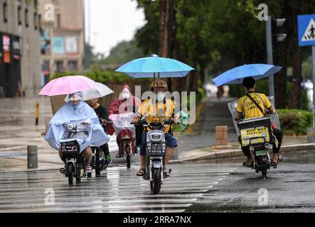 210720 -- SHENZHEN, 20 de julio de 2021 -- Los residentes montan bicicletas eléctricas bajo la lluvia en Shenzhen, provincia de Guangdong del sur de China, 19 de julio de 2021. Se pronostica que el tifón Cempaka, el séptimo de este año, tocará tierra en la costa de la provincia de Guangdong, en el sur de China, el martes, según las autoridades meteorológicas provinciales. Cempaka, fortaleciéndose en un tifón el lunes por la mañana, se acercará lentamente a la región costera entre el estuario del río Perla y el oeste de Guangdong, con su intensidad aumentando gradualmente, y tocará tierra entre las ciudades de Zhuhai y Maoming entre el martes por la tarde y el martes Foto de stock