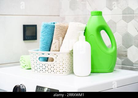 Toallas limpias y detergente en la lavadora en la lavandería o el baño. Foto de stock