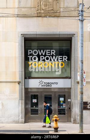 Toronto, Canadá, Una persona camina por el Toronto Hydro Building. Un texto dice Power to Power Toronto Foto de stock