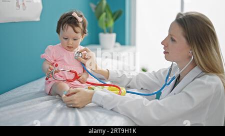 Pediatra de madre e hija examinando el pecho del bebé en la clínica Foto de stock
