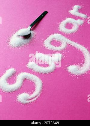 La palabra azúcar se deletrea con azúcar sobre un fondo rosa Foto de stock
