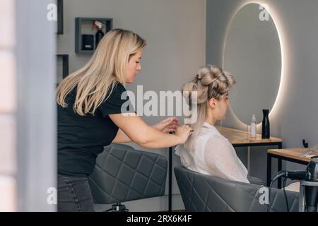 Peluquería peinando el pelo de la mujer en el salón Foto de stock