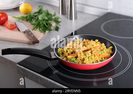 Sabroso arroz con carne y verduras en sartén en placa de inducción Foto de stock