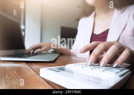 Mujer de negocios analizando gráficos de inversión con calculadora portátil. Contabilidad y tecnología en office.Business Gente usando LAP Foto de stock
