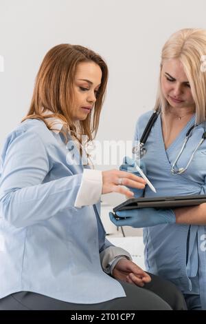 Plan médico: Un médico en una tableta le informa a una mujer sobre un plan de tratamiento y las formas de mejorar su salud. Ayuda de un experto: El médico destaca los resultados Foto de stock
