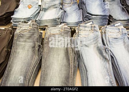 Jeans plegados en los estantes en la tienda minorista Foto de stock