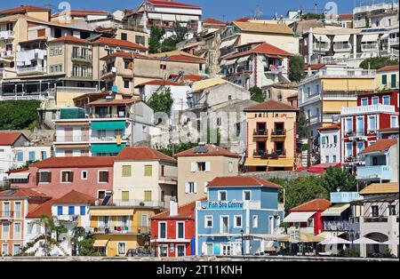 Las coloridas casas y restaurantes junto al acantilado dan al pintoresco puerto de Parga, una ciudad costera en la región de Epiro, en el noroeste de Grecia continental Foto de stock