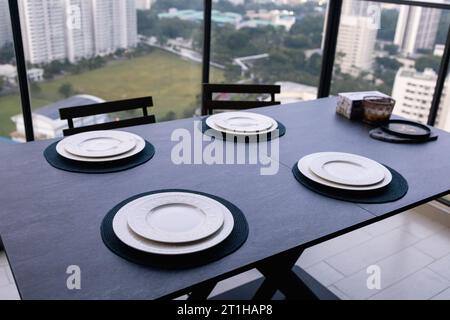 Un restaurante con una vista de la ciudad, que consta de sillas modernas y una mesa oscura. Foto de stock