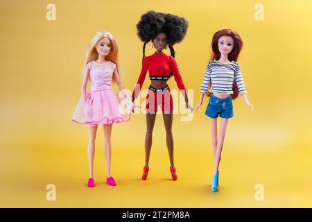 9 de octubre de 2023. Barnaul, Rusia: Tres muñecas rubias, afroamericanas y pelirrojas sobre un fondo amarillo. Barbie y sus amigos. Foto de stock