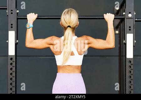 Mujer fuerte haciendo pull ups en barra en estudio Foto de stock