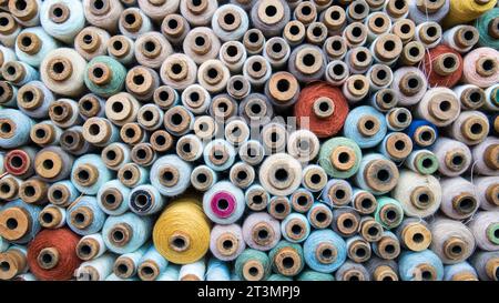 Carretes de hilo de diferentes tamaños y colores en una tienda de costura Foto de stock