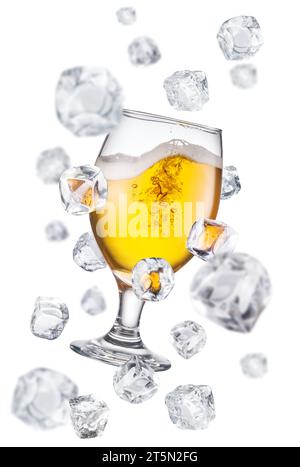 Copa de cerveza rodeada de cubitos de hielo voladores. Imagen conceptual de vidrio de cerveza enfriando. Foto de stock